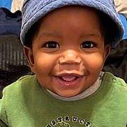 Messiah is registered to the contest to win money with this photo: baby, child, smiling, hat, blue_hat, green_shirt, construction_truck, cute, portrait, face, happy, indoors, closeup, toddler, clothing, person, headwear, joyful, young_child, expressive