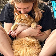 Milo is registered to the contest to win money with this photo: person, cat, orange_cat, fluffy, hugging, affection, outdoor, nature, casual_clothing, black_shirt, legs, hands, pet, cute, relaxed, close_up, warm_lighting, love, animal, human