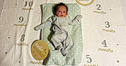 Rayla joined the competition — help win amazing prizes! baby, infant, onesie, milestone_blanket, months, wooden_sign, hello_world, cushion, star_pattern, lying_down, newborn, baby_clothing, baby_bedding, indoors, portrait, cute, child, celebration, first_month, soft_lighting