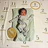baby, infant, onesie, milestone_blanket, months, wooden_sign, hello_world, cushion, star_pattern, lying_down, newborn, baby_clothing, baby_bedding, indoors, portrait, cute, child, celebration, first_month, soft_lighting