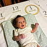 baby, infant, milestone_blanket, pillow, star_pattern, wooden_furniture, clothing, newborn, lying_down, expression, cute, face, head, hand, indoor, bed, blanket, months, number, person