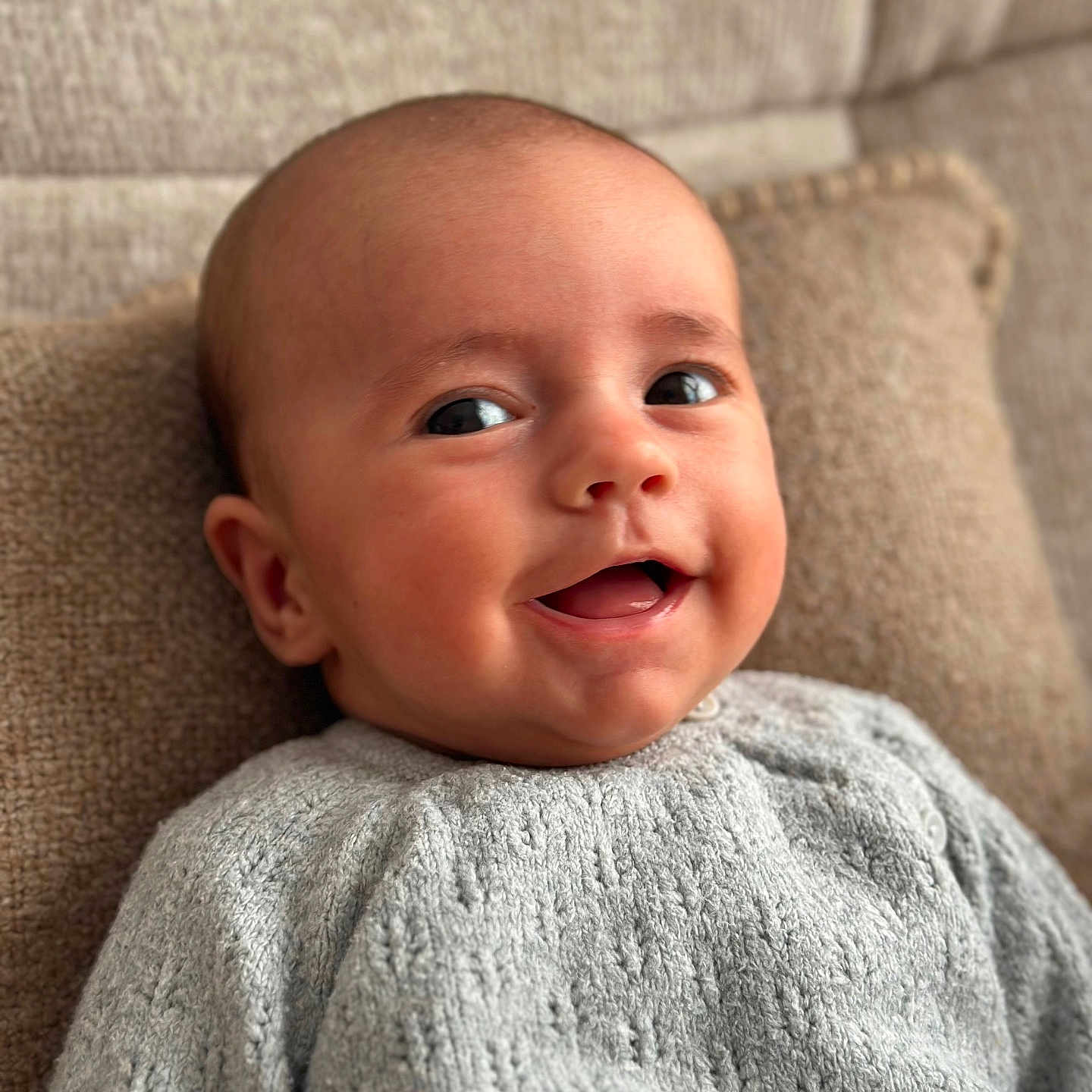 Emilio participe au concours pour gagner de l'argent avec cette photo : baby, child, closeup, cozy, cushion, cute, eyes, face, happy, head, indoors, infant, knitted_sweater, person, portrait, sitting, skin, smile, soft_light, young