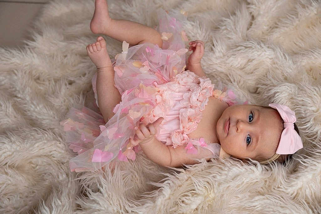 Alba a rejoint le concours — aidez-le/la à gagner de superbes lots ! baby, infant, pink_dress, headband, bow, blue_eyes, fluffy_rug, soft_texture, lying_down, cute, adorable, child, portrait, baby_girl, tulle, butterfly_decorations, skin, small_hands, small_feet, calm