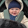 baby, smile, hat, jacket, blanket, face, child, infant, warm_clothing, hood, blue_eyes, knitwear, baby_carrier, outdoor, portrait, cute, happy, cozy, closeup, toddler