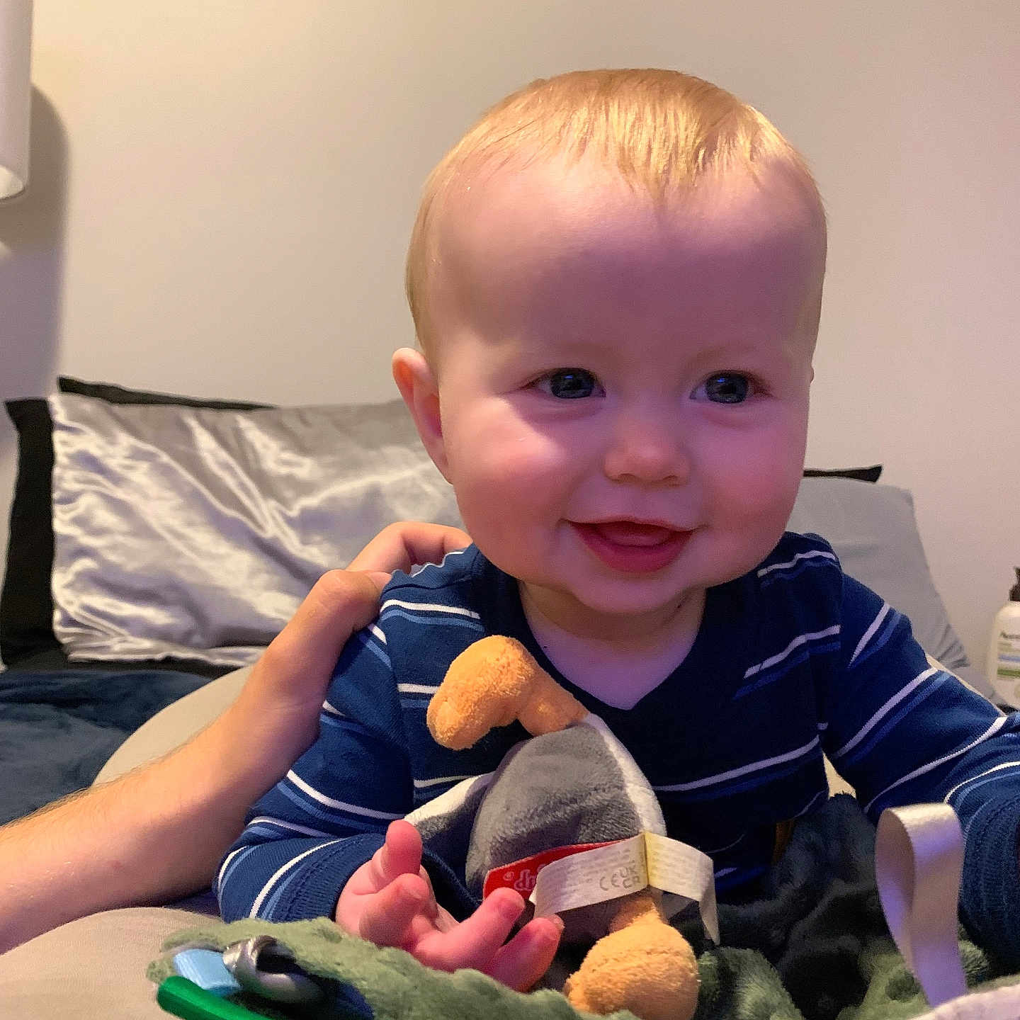 Emerson is registered to the contest to win money with this photo: baby, blanket, child, comfort, couch, cute, face, hand, happy, human, indoor, infant, person, pillow, plush_toy, portrait, smile, soft_toy, striped_clothing, young_child