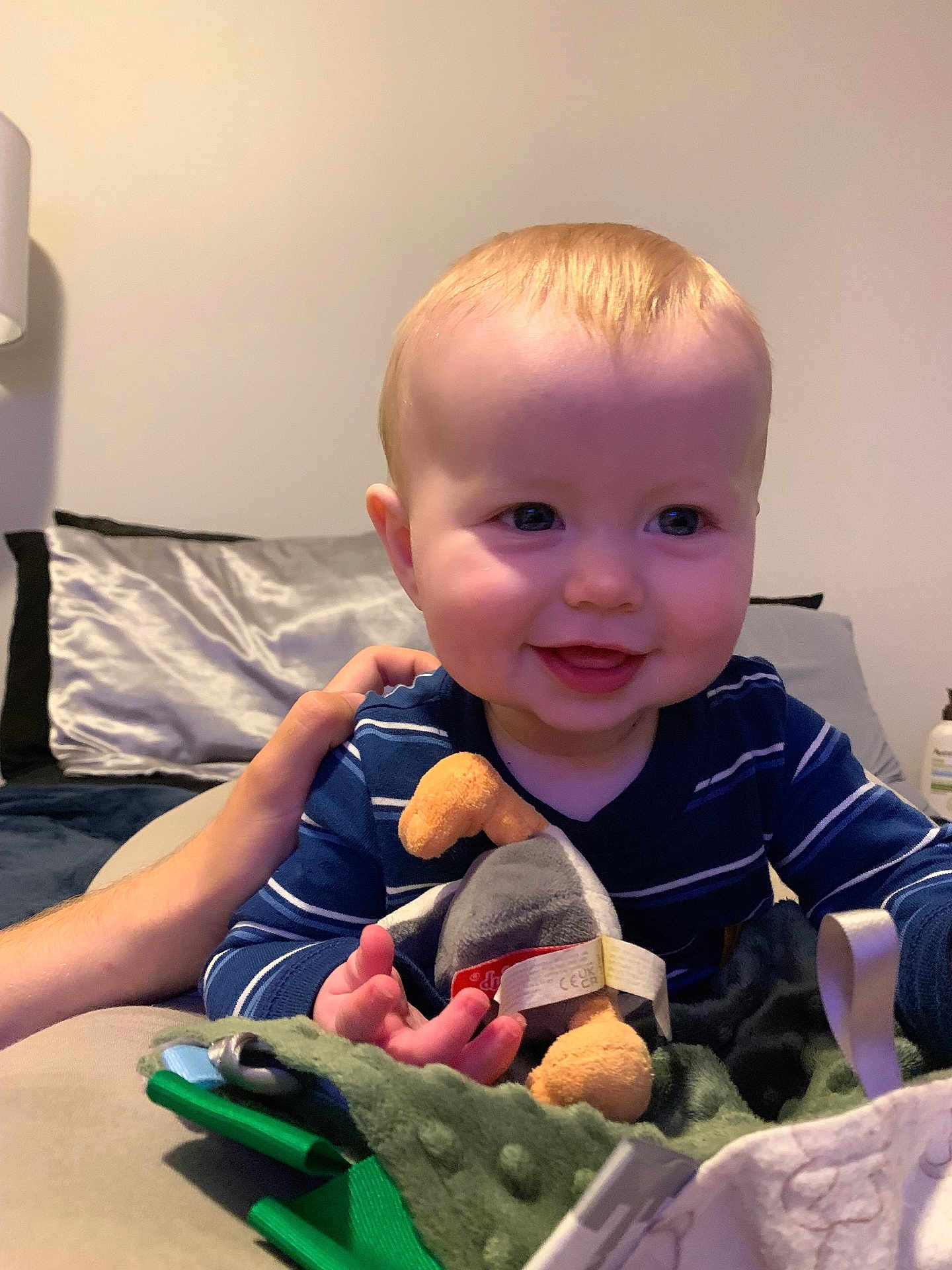 Emerson is registered to the contest to win money with this photo: baby, child, smile, plush_toy, striped_clothing, hand, blanket, pillow, indoor, person, face, happy, infant, couch, soft_toy, young_child, cute, comfort, human, portrait