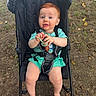 Liam joined the competition — help win amazing prizes! baby, child, stroller, outdoor, grass, leaves, pacifier, red_hair, blue_eyes, teal_clothing, barefoot, infant, seatbelt, nature, person, sitting, cute, curious, ground, playful