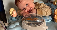 Liam is registered to the contest to win money with this photo: baby, child, red_hair, activity_center, toy, penguin_toy, blue, striped_clothing, happy, cute, indoor, floor, wooden_floor, playing, smiling, infant, face, hands, chewing, soft_toys