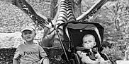 Mirann participe au concours pour gagner de l'argent avec cette photo : baby, bench, black_and_white, child, dragon, expression, hat, nature, outdoor, pacifier, park, person, playful, sculpture, sneakers, statue, stone, stroller, summer_clothing, trees