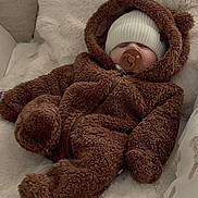 Amaya is registered to the contest to win money with this photo: baby, infant, sleeping, pacifier, bear_suit, hood, knit_hat, white_blanket, fuzzy_clothing, soft_texture, cute, cozy, indoor, couch, plush, child, warm, relaxed, face, person