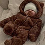 baby, infant, sleeping, pacifier, bear_suit, hood, knit_hat, white_blanket, fuzzy_clothing, soft_texture, cute, cozy, indoor, couch, plush, child, warm, relaxed, face, person