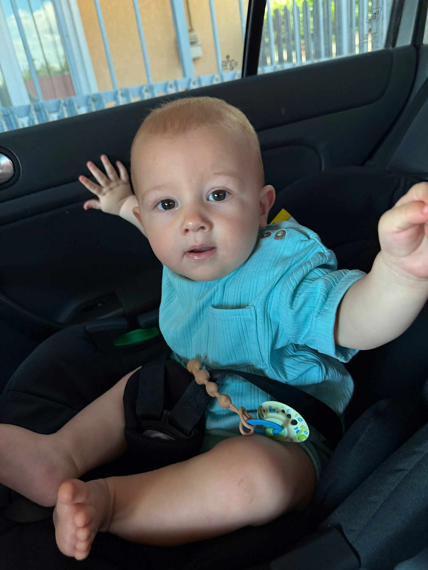 Dominic Nicolas is registered to the contest to win money with this photo: baby, child, car_seat, blue_shirt, pacifier, infant, inside_car, seatbelt, curious, reaching_hand, cute, young_child, safety, car_interior, portrait, face, legs, foot, expression, casual