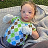Javan Criswell is registered to the contest to win money with this photo: argyle_shirt, baby, blanket, blue_eyes, colorful_clothing, curly_hair, cute, daylight, grass, hand, infant, knitted, lying_down, mittens, outdoor, person, playful, portrait, soft_texture, young_child