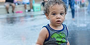 Adam joined the competition — help win amazing prizes! blurred_background, casual_clothing, child, curly_hair, daylight, expression, outdoor, pants, people, person, photography, play, public_space, standing, tank_top, toddler, urban_park, water, water_fountain, young_child