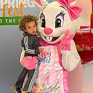 Adam is registered to the contest to win money with this photo: child, toddler, mascot, easter_bunny, costume, balloons, indoor, curly_hair, apron, pink_bow, celebration, holiday, spring, decorations, person, smile, holding, floor, event, fun