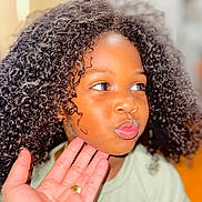 Adhara is registered to the contest to win money with this photo: casual, child, closeup, curly_hair, cute, expression, face, focus, hair, hand, human, indoors, light, person, playful, portrait, pout, skin, smile, young
