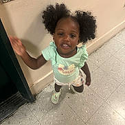 Adhara joined the competition — help win amazing prizes! toddler, child, girl, hair, pigtails, smiling, hallway, floor, tile_floor, wall, green_shirt, shorts, footwear, motion_blur, indoor, person, cute, playful, happy, gesture