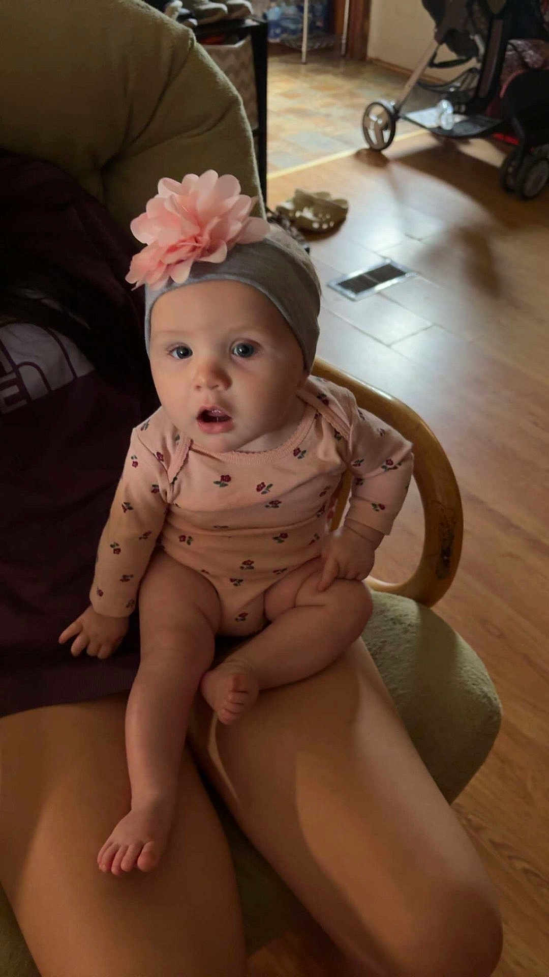 Mckinleigh joined the competition — help win amazing prizes! baby, child, infant, headband, flower, pink, gray, onesie, person, legs, hand, chair, wood_floor, indoor, stroller, curious, sitting, expression, cute, casual