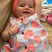 Mckinleigh is registered to the contest to win money with this photo: baby, child, smiling, headband, dress, patterned_clothing, toy, plush_toy, cushion, striped_fabric, indoor, cute, happy, infant, raised_arm, buttoned_dress, soft_toys, colorful, lying_down, portrait