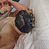 dog, man, smile, lying_down, indoor, blanket, playful, pet, canine, relaxed, cozy, closeup, brown_dog, teeth, face, expression, human, resting, friendship, funny