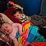 child, baby, toddler, sleeping, blanket, colorful_blanket, pillow, bed, bedroom, camo_clothing, plaid_blanket, bedding, cozy, sibling, interior, wall, nap, relaxed, clothes_pile, home