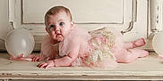 Emersyn is registered to the contest to win money with this photo: baby, infant, pink_dress, frilly_dress, balloon, ribbon, vintage_furniture, wooden_surface, blue_eyes, curious_expression, chubby_cheeks, lying_down, indoor, portrait, child, cute, soft_lighting, decorative, closeup, adorable