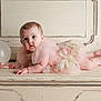 baby, infant, pink_dress, frilly_dress, balloon, ribbon, vintage_furniture, wooden_surface, blue_eyes, curious_expression, chubby_cheeks, lying_down, indoor, portrait, child, cute, soft_lighting, decorative, closeup, adorable