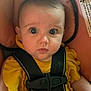 baby, child, car_seat, yellow_clothing, straps, wide_eyes, curious, indoor, seatbelt, infant, portrait, close_up, face, cute, young_child, safety, pink_background, expression, looking_at_camera, person