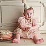 baby, child, cake, birthday_hat, pink_dress, messy, frosting, sitting, indoors, cute, party, celebration, portrait, foot, hand, face, expression, wooden_floor, wall_panel, cake_stand