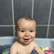 Maël a rejoint le concours — aidez-le/la à gagner de superbes lots ! baby, child, smiling, bath, water, toy, blue_eyes, happy, skin, head, face, arm, tiled_wall, bathroom, cute, infant, playful, wet, person, young