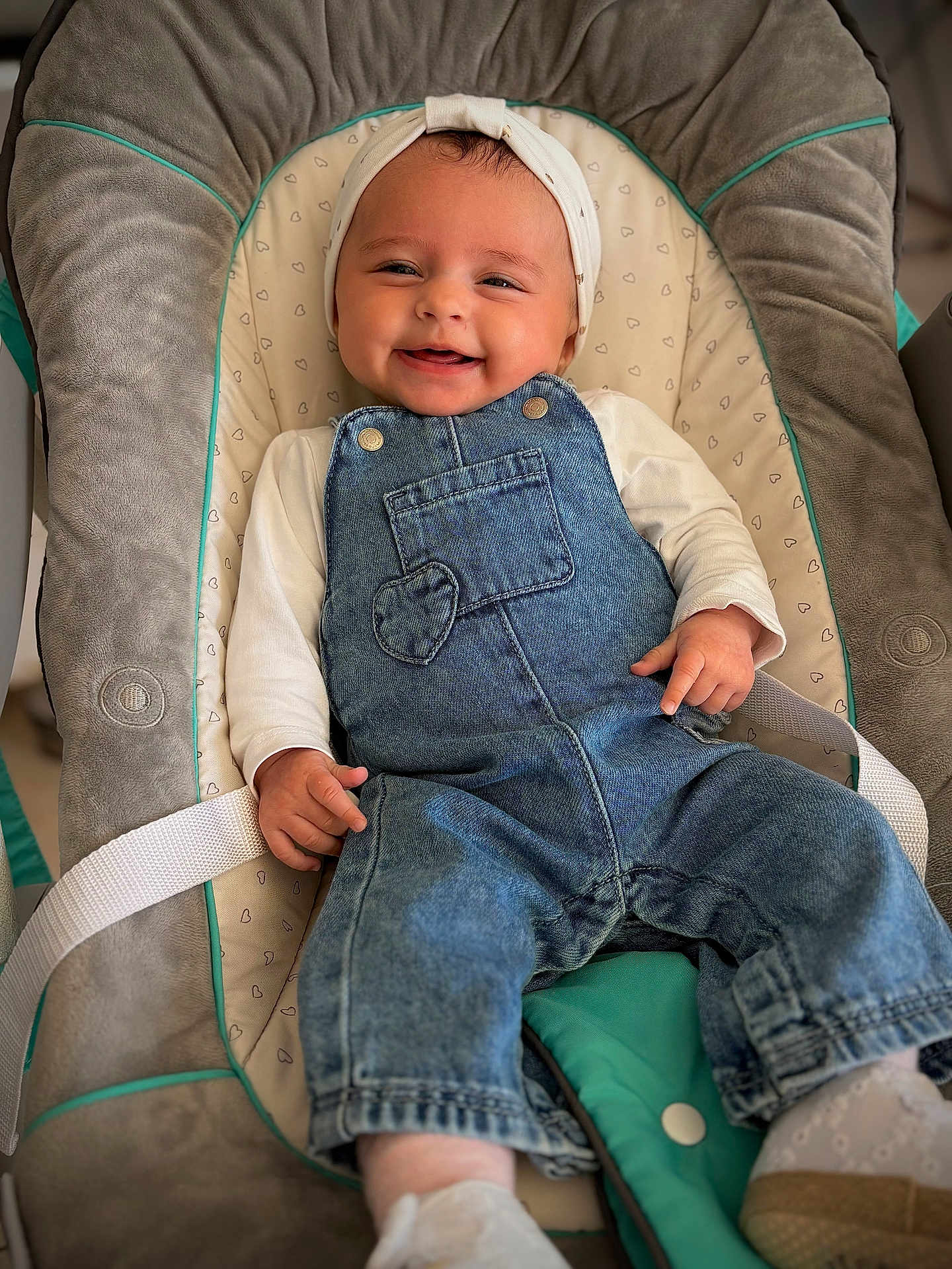 Maria a rejoint le concours — aidez-le/la à gagner de superbes lots ! baby, infant, smiling, denim_overalls, headband, bouncer, baby_seat, heart_pattern, strap, white_onesie, hands, shoes, portrait, cute, happy, indoor, soft_fabric, closeup, eyes, skin