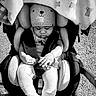 baby, blanket, child, clothing, cute, grayscale, infant, knit_hat, outdoor, peaceful, person, portrait, seat_belt, small_object, socks, stroller, sunlight, teddy_bear_pattern, toy, warm_clothing