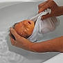 baby, infant, swaddled, hands, bathtub, water, towel, bath, person, skin, white_cloth, relaxation, newborn, care, cleaning, gentle, indoor, parent, closeup, human