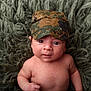 baby, infant, child, face, headwear, cap, camouflage, skin, bare_chest, expression, curious, lying_down, blanket, texture, closeup, portrait, indoors, young, person, cute