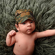 Santiago joined the competition — help win amazing prizes! arm, baby, camo, camouflage, child, cute, expression, fluffy, green, hat, headwear, indoors, infant, looking, person, portrait, pose, rug, skin, young