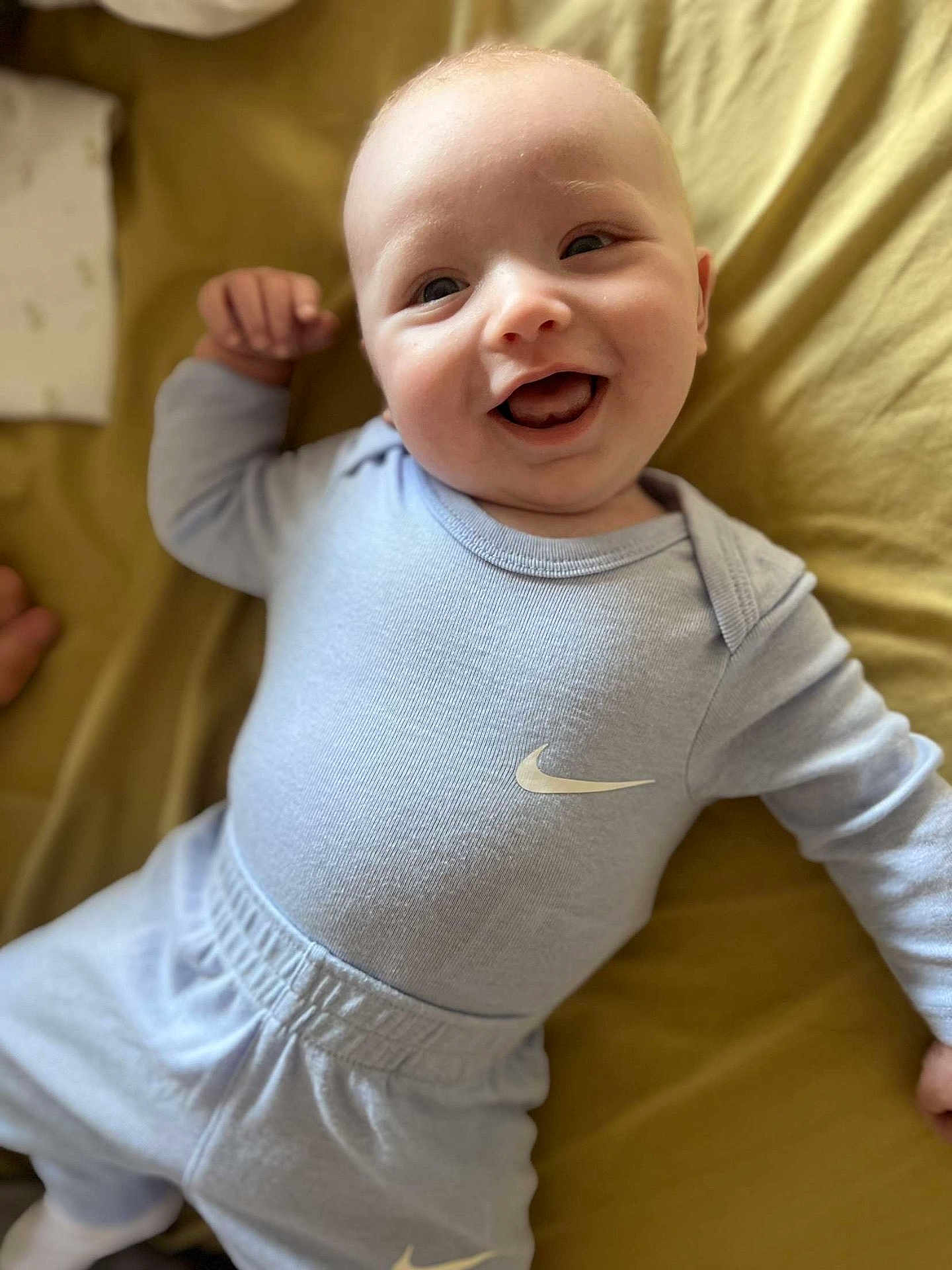Arlo-Lee joined the competition — help win amazing prizes! baby, smiling, infant, clothing, nike, onesie, pants, happy, lying_down, blanket, child, cute, portrait, face, human, apparel, sleeves, feet, indoor, young
