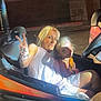 adult, amusement_park, blonde_hair, bumper_car, casual_clothing, child, dark_background, fun, hand_gesture, leisure, lighting, night, outdoor, peace_sign, person, ride, seat, shadow, smile, vehicle