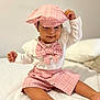 toddler, child, baby, hat, cap, bow_tie, pink, plaid, shorts, white_sweater, sitting, indoors, bed, blanket, foot, smile, cute, fashion, portrait, playful