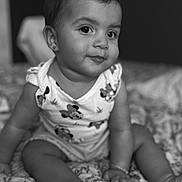 Louna participe au concours pour gagner de l'argent avec cette photo : baby, black_and_white, blanket, child, clothing, cute, earring, face, foot, hand, indoors, infant, monochrome, patterned, person, portrait, room, sitting, smile, young