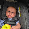 Jaxon joined the competition — help win amazing prizes! baby, infant, child, car_seat, seated, face, portrait, wide_eyed, puzzled, indoors, vehicle, safety_harness, gray_upholstery, apple, fruit, hand, casual_clothing, close_up, photography, safe