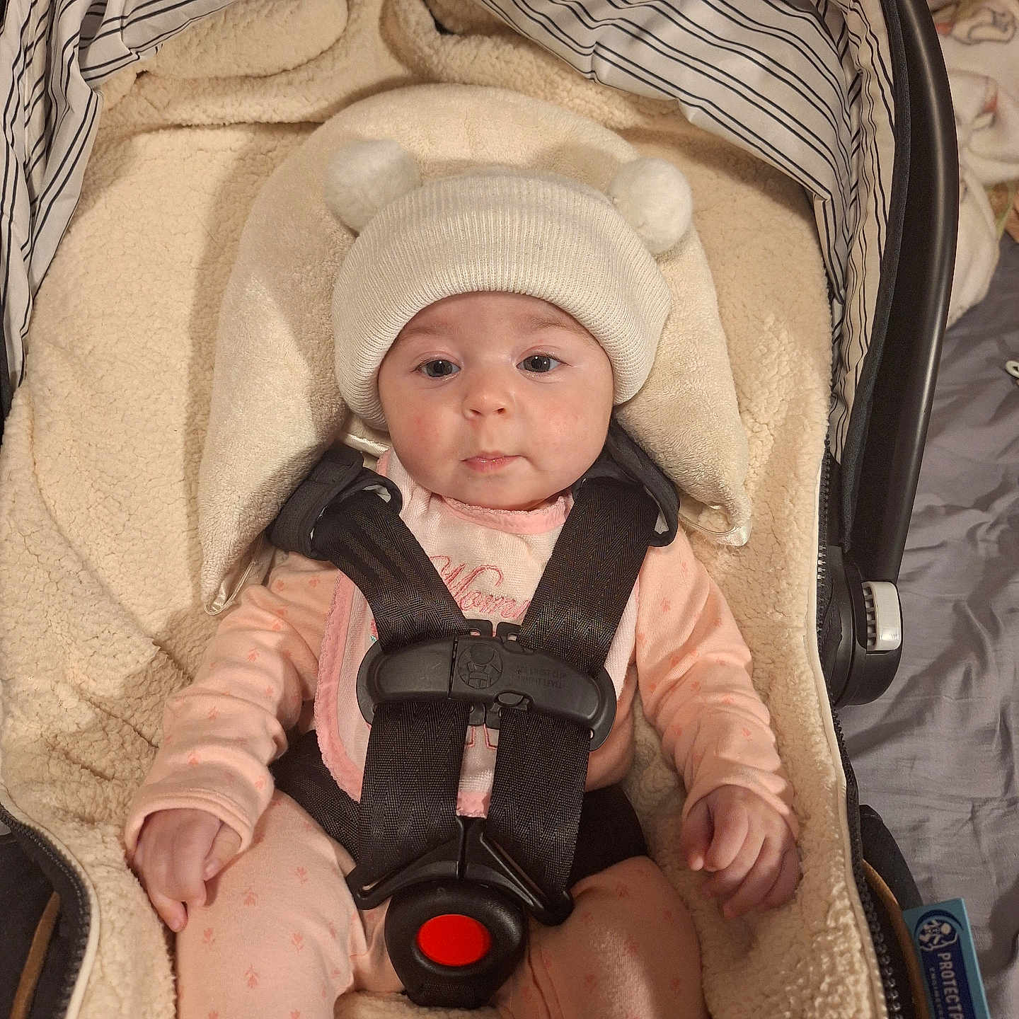 Haylee M is registered to the contest to win money with this photo: baby, blanket, car_seat, child, clothing, cozy, cute, expression, face, hat, headwear, indoors, infant, newborn, person, pink_pajamas, safety_harness, seated, soft, straps
