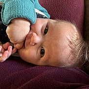 Vincent is registered to the contest to win money with this photo: awake, baby, blanket, close_up, couch, cozy, eyes, face, finger, hair, hand, indoor, infant, lying_down, maroon_blanket, portrait, skin, sleeve, teal_sweatshirt, thumb