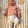 baby, smiling, infant, blanket, clothing, pants, socks, face, portrait, lying_down, cute, wooden_plaque, milestone, soft_texture, child, happy, indoors, person, pink, white