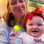 Ella Marie Kutchen is registered to the contest to win money with this photo: baby, child, cozy, decor, face, family, female, hand, happy, holiday, indoor, infant, light, painting, person, portrait, red_headband, smile, sweater, woman