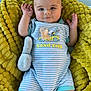baby, infant, blanket, soft_toy, onesie, striped_clothing, smiling, face, hands, feet, cute, cozy, lying_down, blue_background, yellow_blanket, child, indoors, portrait, comfort, relaxed