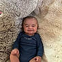baby, infant, smile, onesie, plush_toy, stuffed_animal, cushion, soft_texture, cozy, child, sleepy, happy, comfortable, indoor, closeup, portrait, resting, cute, furry, relaxed