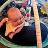 Colby is registered to the contest to win money with this photo: baby, infant, bib, play_gym, toy, cushion, indoor, floor, wooden_floor, child, face, person, colorful, hanging_toy, soft_toy, blanket, home, curious, motion_blur, young_child