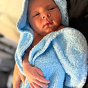 Ronnie joined the competition — help win amazing prizes! newborn, baby, towel, blue_towel, hooded_towel, infant, hand, skin, portrait, person, soft_texture, warm_lighting, closeup, cradling, resting, indoors, gentle, peaceful, child, cute