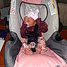 Aaliyah is registered to the contest to win money with this photo: baby, infant, sleeping, car_seat, safety_harness, bow, pacifier, pink, clothing, blanket, feet, indoors, portrait, seated, resting, newborn, buckle, fabric, furniture, photograph