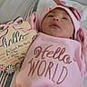 newborn, baby, infant, portrait, pink_clothing, pink_hat, bow, bib, blanket, crib, bed, keepsake_sign, hello_world, sleeping, face, indoors, close_up, birth_announcement, cute, family_milestone